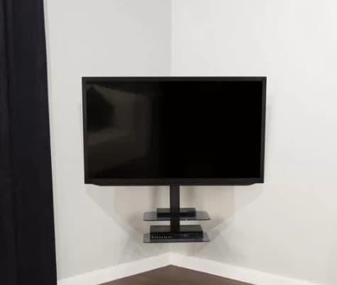 TV mounted beside a corner on a narrow wall with a floating shelf below for streaming devices